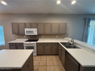 Kitchen featuring white appliances, gray cabinetry