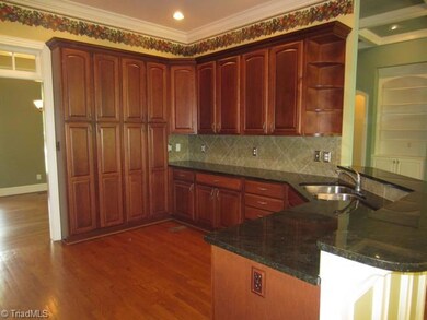 Kitchen.  Hardwood floors and the furniture-like finish on the cabinets make this a warm, hospitable room.  The long cabinets cover the pantry and the tiled backsplash and granite counters create a easy to clean workspace.  Along breakfast bar allows seating area for those guests who are always hanging out in the kitchen!
