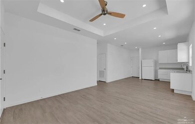 Unfurnished living room with a raised ceiling, recessed lighting, light wood finished floors, and a ceiling fan