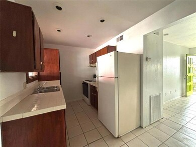 Kitchen featuring tile counters, a sink, white appliances, and visible vents
