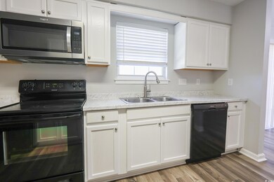 Kitchen with light countertops, white cabinets, a 