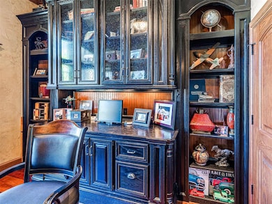 Office space with a textured wall, baseboards, wood finished floors, and built in study area