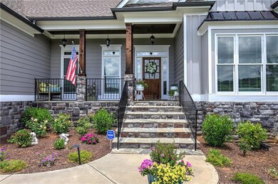 Entrance to property featuring stone siding, covered porch, and a standing seam roof