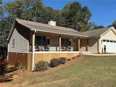 Single story home featuring a porch, a garage, a shingled roof, a front lawn, and a chimney