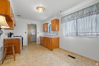 Kitchen featuring brown cabinetry, visible vents, a sink, light countertops, and range