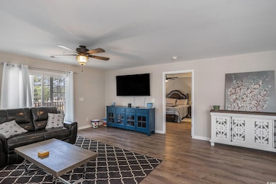 Living room with ceiling fan, baseboards, and wood finished floors