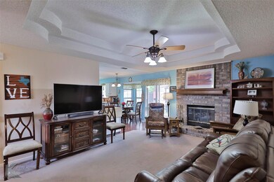 Carpeted living room with a fireplace, ceiling fan