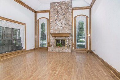 Den with laminate wood floors, wood burning fireplace, beautiful wood molding accents and high ceiling.