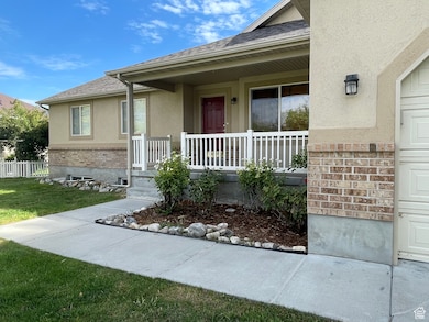 Entrance to property with roof with shingles, brick siding, stucco siding, a porch, and a lawn