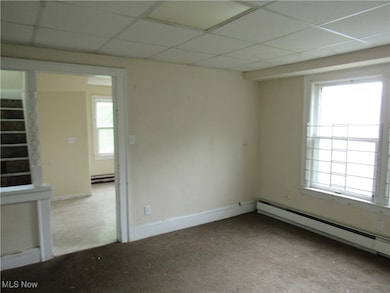 Spare room featuring a baseboard heating unit and a drop ceiling