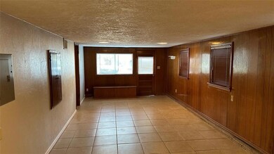 Entryway featuring electric panel, wood walls, lig