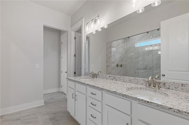 Full bathroom featuring a marble finish shower, light marble finish flooring, and double vanity