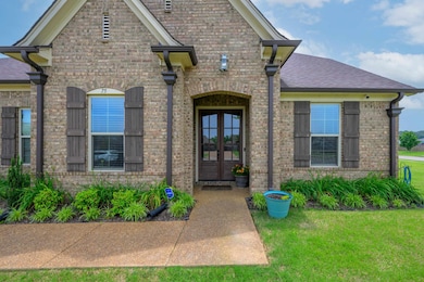 Entrance to property with french doors, brick siding, a lawn, and roof with shingles