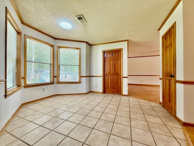Breakfast Area with ornamental molding, a textured ceiling, light tile patterned floors, and baseboards