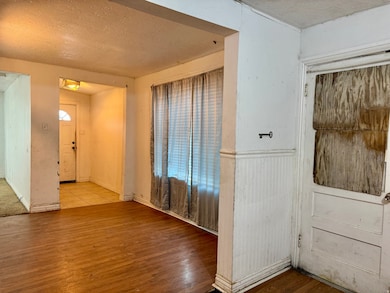 Spare room featuring wood finished floors, a textured ceiling, and wainscoting