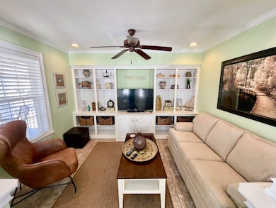 Living room with ceiling fan, crown molding, and r