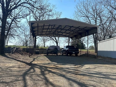 View of parking / parking lot with driveway and a detached carport