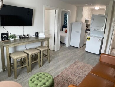 Living room view showcasing entry to two bedrooms and kitchen/laundry area.