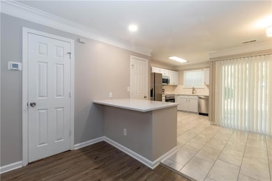 Kitchen featuring white cabinetry, crown molding, a peninsula, stainless steel appliances, and light wood-style flooring