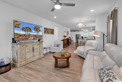 Living room with ceiling fan with notable chandeli