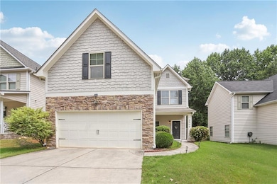 View of front of house featuring stone siding, an attached garage, driveway, and a front yard