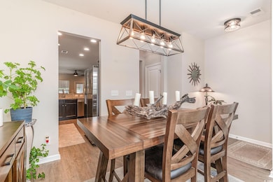 Dining space with ceiling fan and light wood-type 