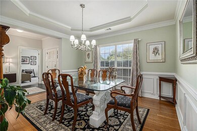 Dining space featuring crown molding, a tray ceiling, a wainscoted wall, a decorative wall, and dark wood-type flooring