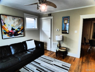Living area with hardwood / wood-style floors, crown molding, and ceiling fan