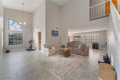 Living room featuring a towering ceiling, plenty of natural light, and a chandelier