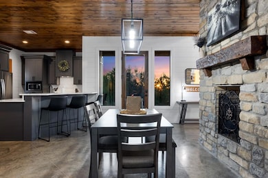 Dining space featuring a fireplace, wooden ceiling, concrete floors, and recessed lighting