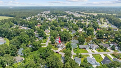 Aerial view of property and surrounding area with nearby suburban area and a heavily wooded area