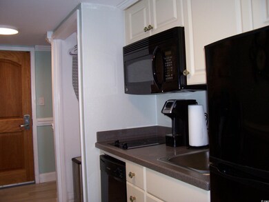 Kitchen featuring white cabinets, wood finished fl