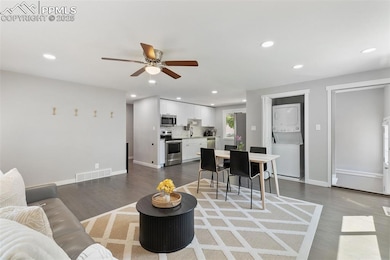 Living room with recessed lighting, dark wood-style floors, stacked washer / drying machine, and a ceiling fan