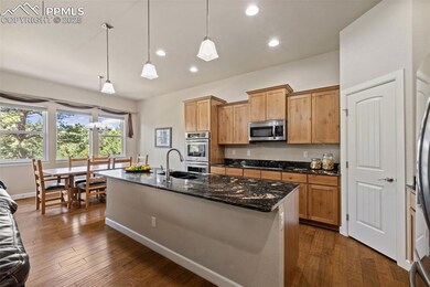 Kitchen with appliances with stainless steel finishes, recessed lighting, dark wood-style flooring, a kitchen island with sink, and hanging light fixtures