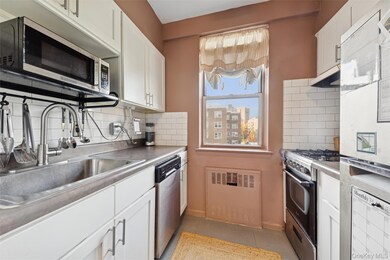 Kitchen with stainless steel appliances, white cabinets, light tile patterned floors, tasteful backsplash, and under cabinet range hood