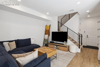 Living area with stairs, access to covered patio, Luxury Vinyl Tile flooring, and recessed lighting