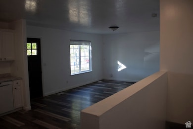 Unfurnished dining area with dark wood-style floors and baseboards