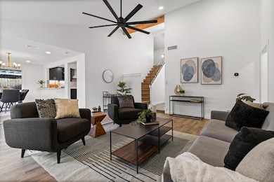 Living area featuring recessed lighting, light wood finished floors, high vaulted ceiling, stairway, and a ceiling fan