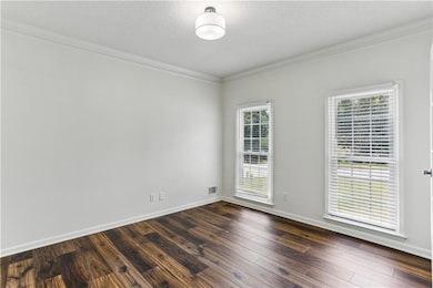 Unfurnished room with healthy amount of natural light, ornamental molding, dark wood-style flooring, and baseboards