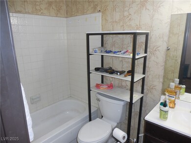 Bathroom featuring wallpapered walls, vanity, and