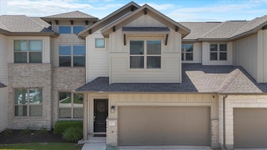 Townhome / multi-family property with board and batten siding, roof with shingles, concrete driveway, and brick siding