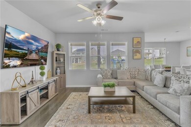 Living area with wood finished floors, ceiling fan, baseboards, and a chandelier