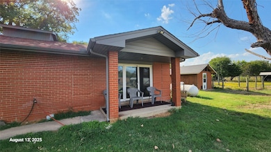 Rear view of property featuring brick siding and covered porch