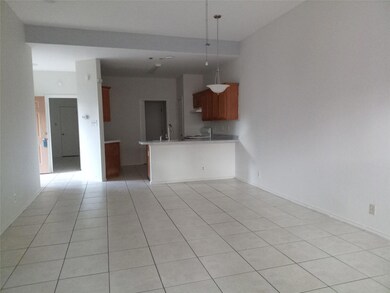 Kitchen featuring brown cabinetry, light countertops, a peninsula, light tile patterned floors, and decorative light fixtures