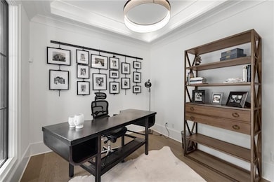 Office space with wood finished floors, a tray ceiling, and ornamental molding