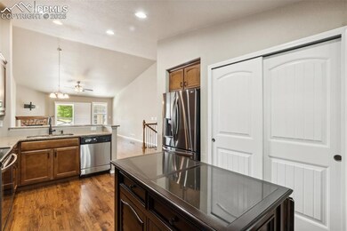 Kitchen with appliances with stainless steel finishes, a sink, recessed lighting, dark wood-type flooring, and vaulted ceiling
