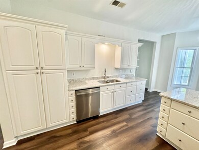 Kitchen featuring white cabinetry, dark hardwood /