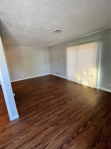 Empty room featuring dark wood-style floors and a textured ceiling