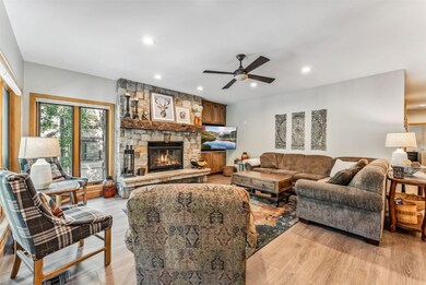 Living room with hardwood floors, a stone fireplac
