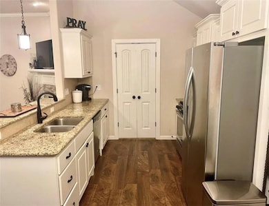 Kitchen featuring sink, stainless steel appliances, light stone countertops, white cabinets, and decorative light fixtures